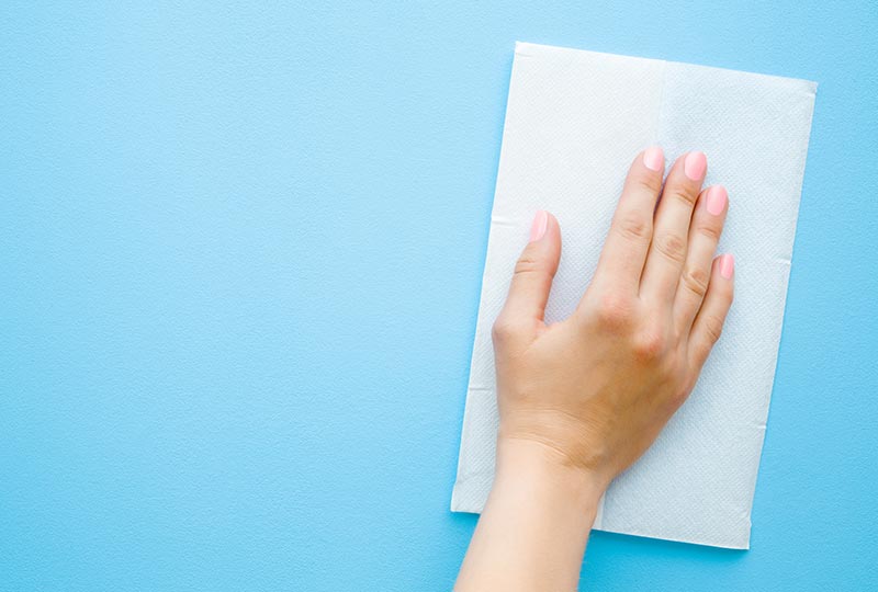 Hand wischt mit einem Tuch eine Oberfläche ab