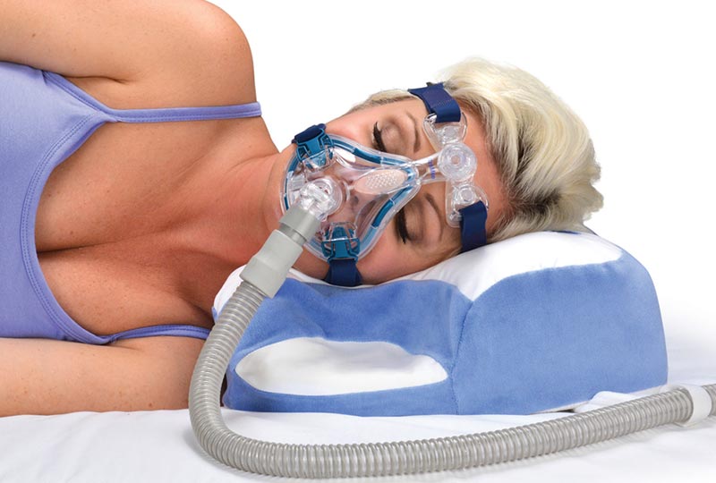 Frau liegt seitlich auf dem CPAP Polster mit einer CPAP Maske auf