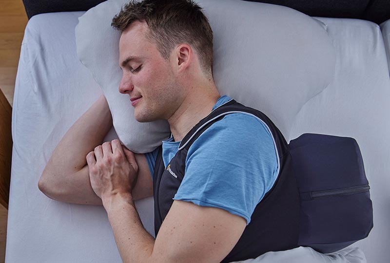 Mann liegt auf der Seite und schläft und hat dabei die Nachtwaechter Schlafweste an