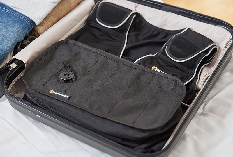 Offener Koffer liegt auf dem Bett, die Nachtwaechter Schlafweste ist darin verpackt